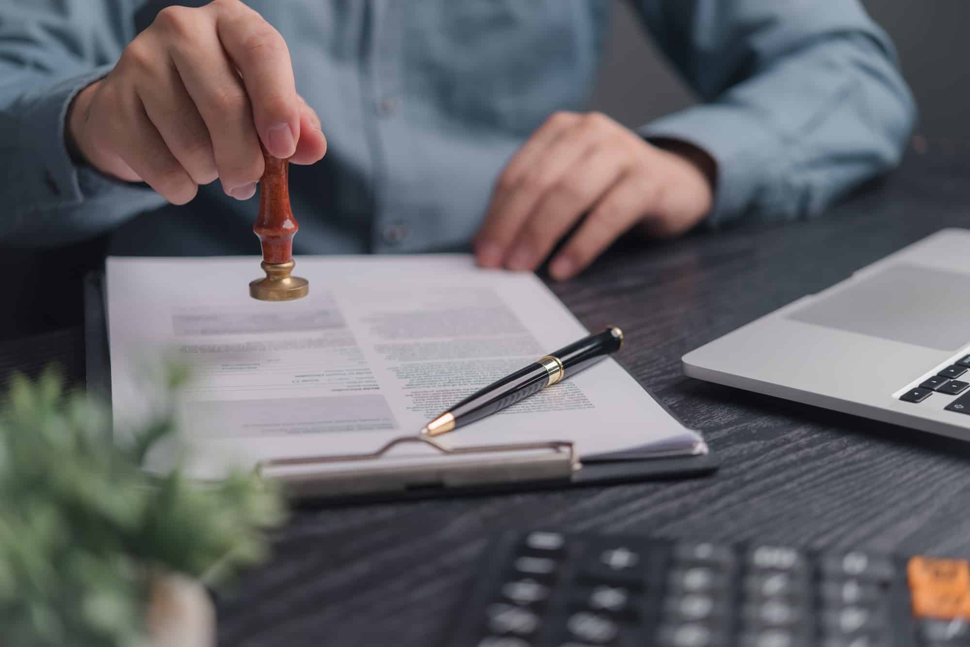 Hand pressing a rubber approval stamp onto a building permit application document